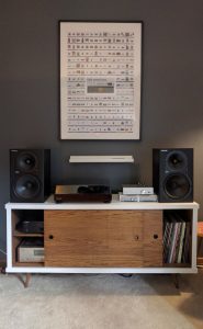 A console with record player, speakers, records, and poster.
